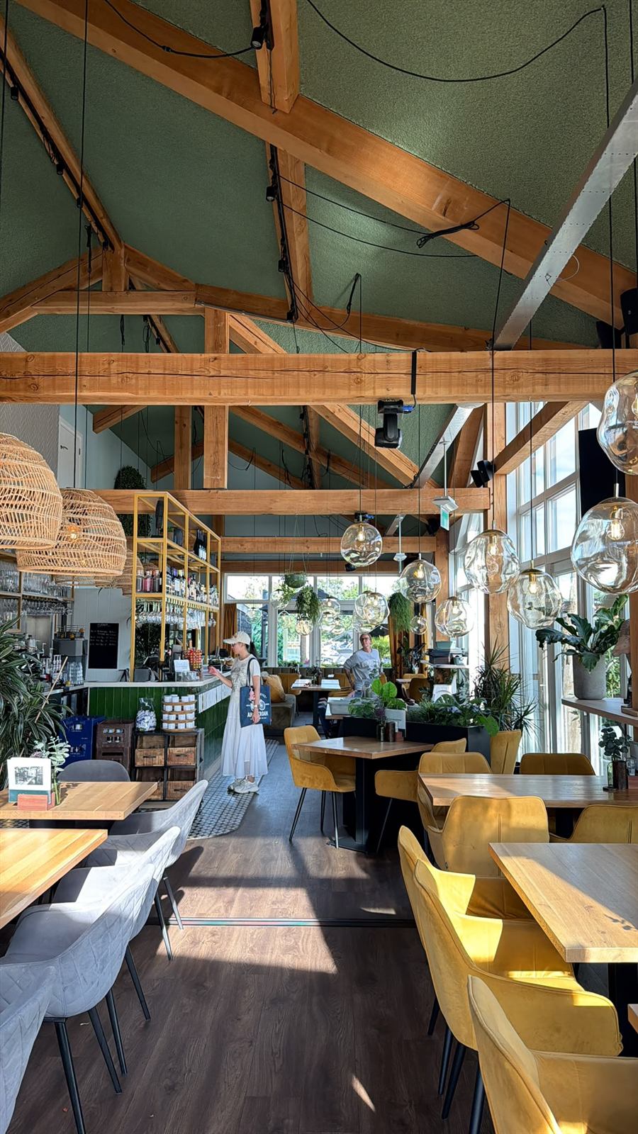 Het interieur van De Eetkamer van Giethoorn met houten spanten, groene wanden en rieten lampen