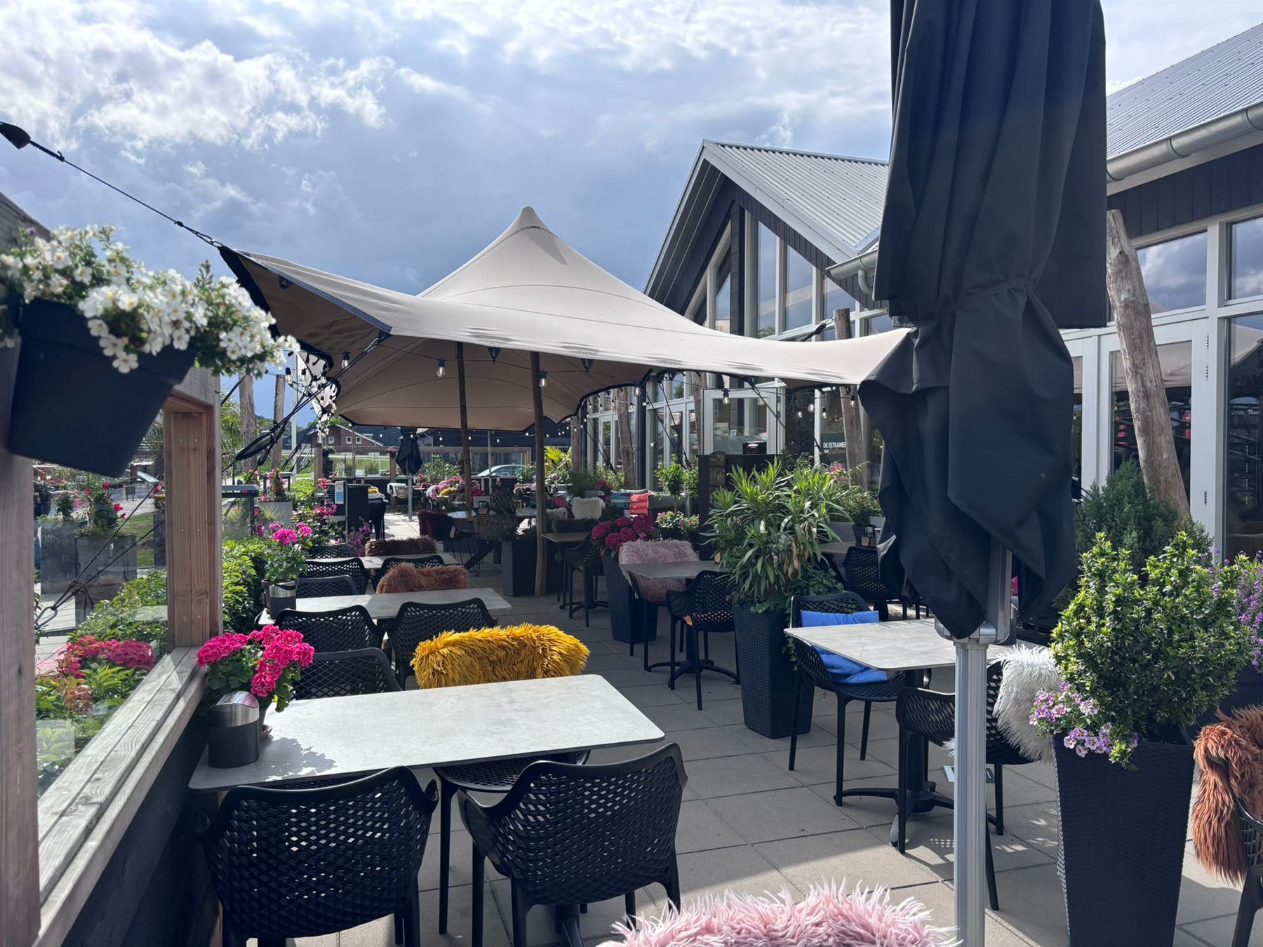 Het terras met bloembakken onder de stretchtenten